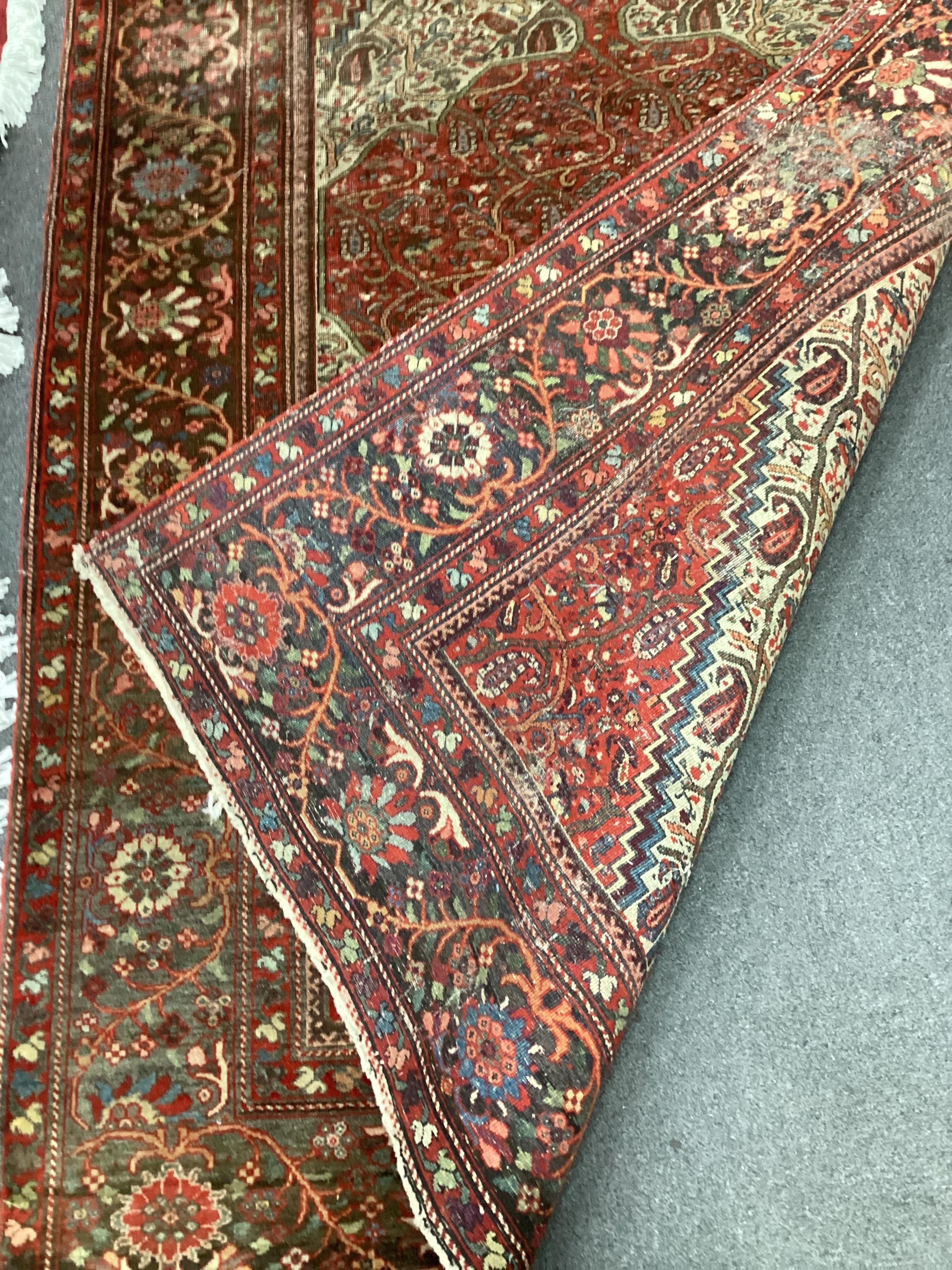 An Isphahan red and cream medallion rug, enclosed by a border of trailing stylised foliage, 200cm x 132cm